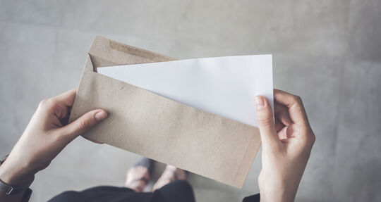 Person nimmt einen Brief aus einem Kuvert | GettyImages / seb_ra
